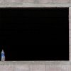 the window of a building under construction. note the water bottle and the man's hand about to pick it up